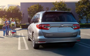 A silver 2024 Honda Odyssey parked in a parking lot, with a family walking up to it near Orangeburg, South Carolina