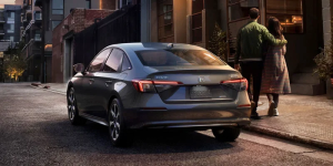 A silver 2025 Honda Civic parked on a city street near two people walking together near Orangeburg, South Carolina